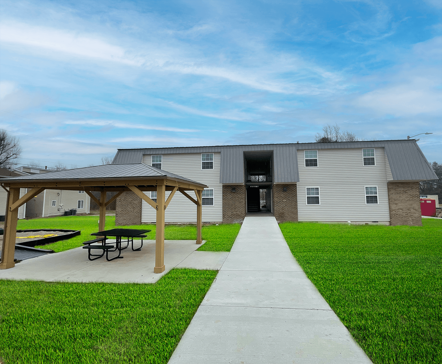 the back of a building with a picnic area and a sidewalk